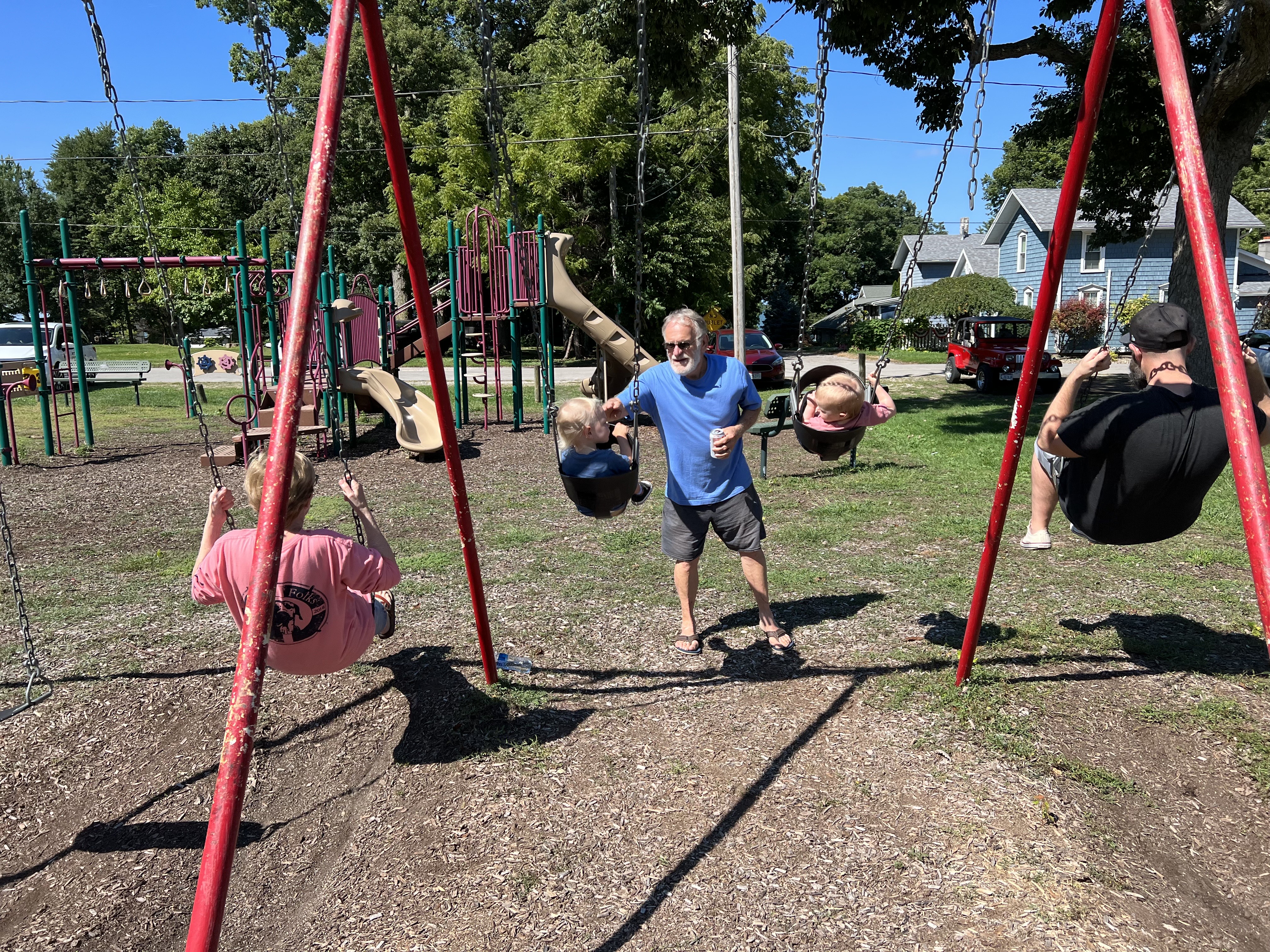 Grandpa pushing the kids on the swings in James Park.